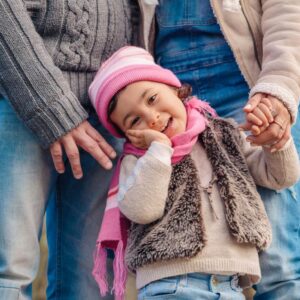 Rodzice trzymający małe dziecko za ręce podczas spaceru