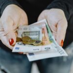 Kobiece dłonie trzymające euro – symboliczne przedstawienie kosztów utrzymania dziecka i alimentów