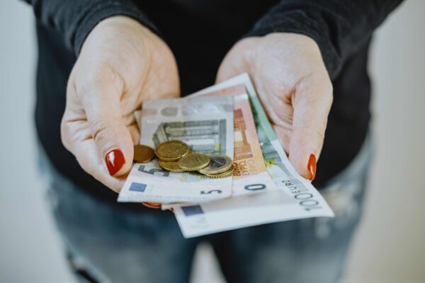 Kobiece dłonie trzymające euro – symboliczne przedstawienie kosztów utrzymania dziecka i alimentów