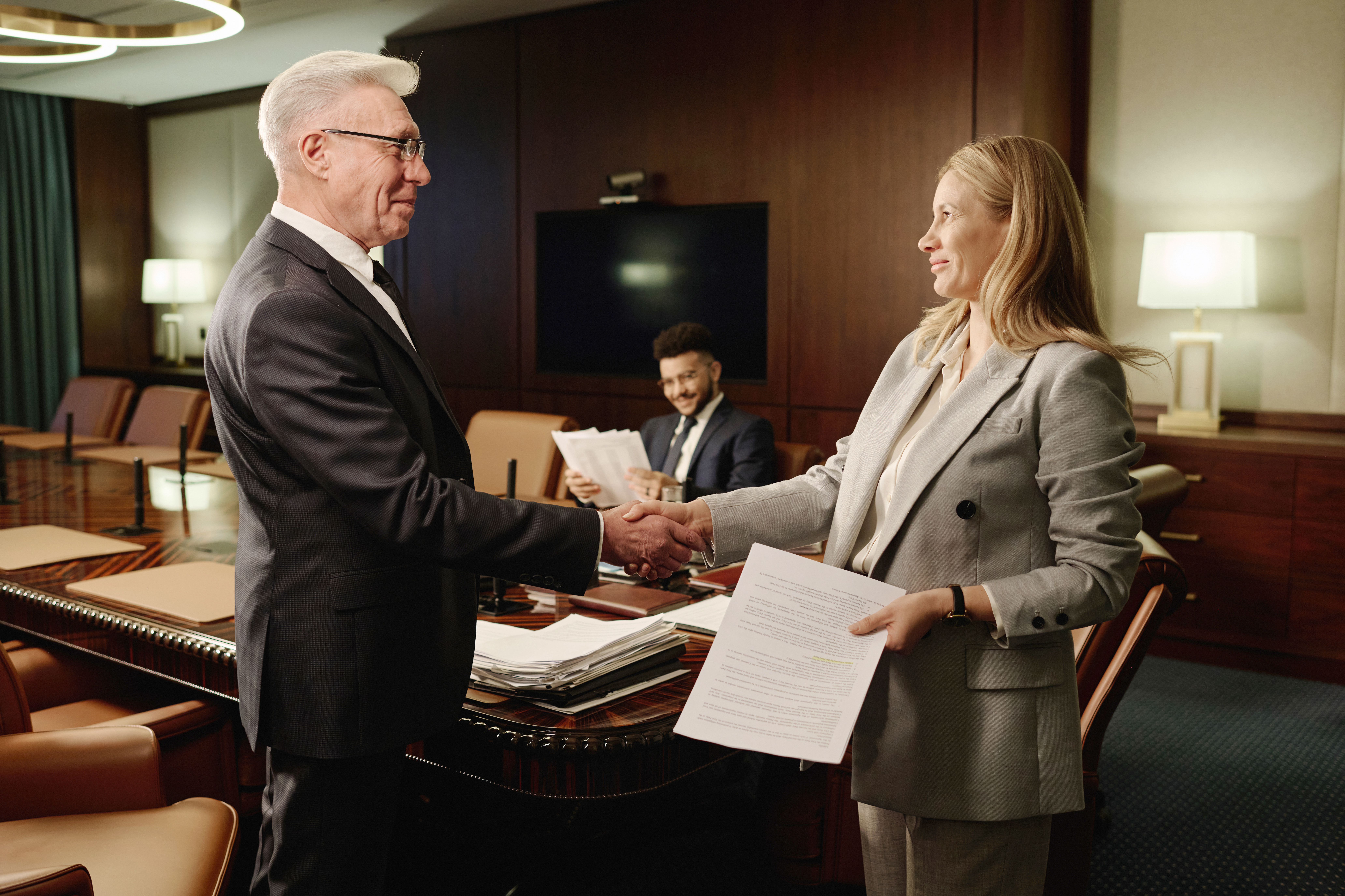 Kobieta i mężczyzna podający sobie rękę podczas formalnego spotkania w urzędzie stanu cywilnego.